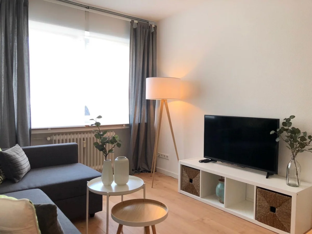 Ein modernes Wohnzimmer mit Sofa, Fernseher und Stehlampe.